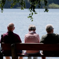 Urlauber sitzen bei sommerlichem Wetter auf Bank
