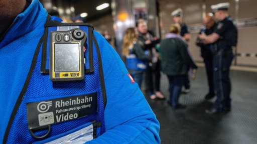 Ein Rheinbahnmitarbeiter mit einer Videokamera an seiner Weste