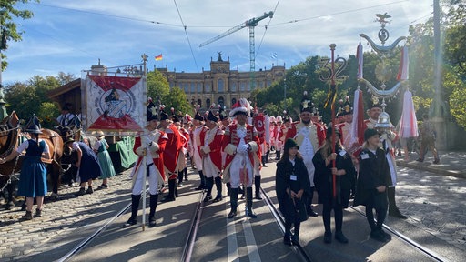 Personen in Kostümen ziehen durch eine Straße