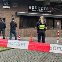 In einem abgesperrten Bereich vor einer Bar in Köln stehen mehrere Einsatzkräfte der Polizei