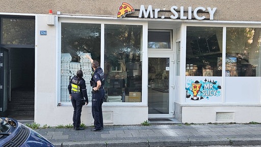 Zwei Polizisten stehen vor dem Geschäft "Mr. Slicy"