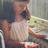 Ein Grundschulkind hat ein Thermometer in der Hand 