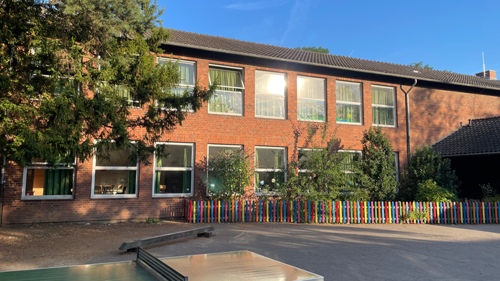 Großer Schulhof mit einer Tischtennisplatte und Schulgebäude