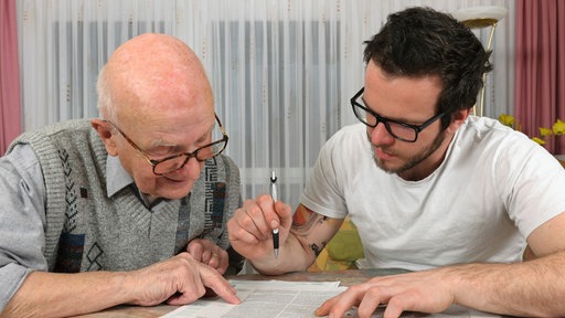 Ein älterer Mann und sein Sohn schauen über einen Vertrag