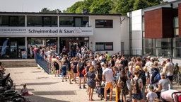 Menschen stehen Schlange am Eingang zum Stadionbad