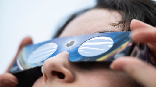 Eine Angestellte eines Fotofachhandelsgeschäfts hat eine Sonnenfinsternis-Brille an
