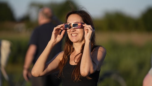 Eine Frau schaut durch eine Sonnenfinsternisbrille