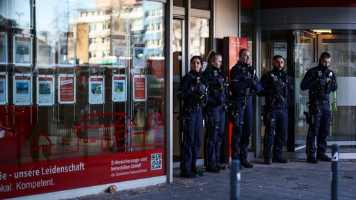 Einsatzkräfte der Polizei stehen vor der Sparkassenfiliale im Stadtteil Buer