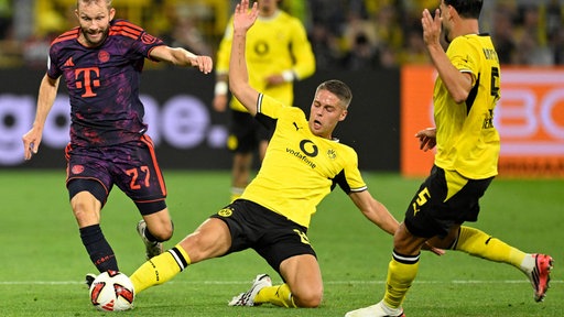 Joey Veerman (Mitte) vom BVB setzt zur Grätsche an.