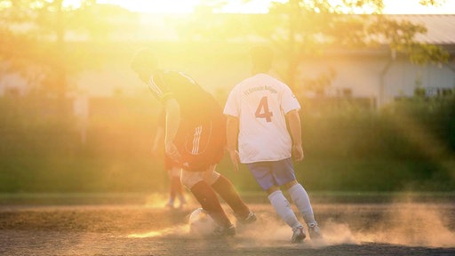 Zwei Kreisliga-Spieler kicken in der Abend-Sonne