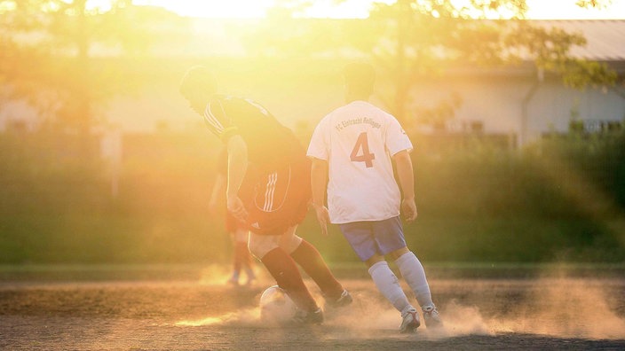 Zwei Kreisliga-Spieler kicken in der Abend-Sonne