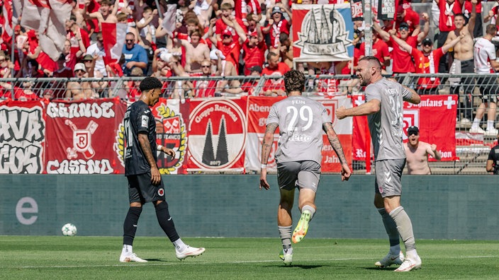 Adrian Fein, Patrick Hobsch und die Regensburger Fans bejubeln das Tor zum 3:1.
