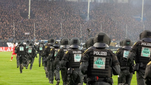 Polizisten rennen auf das Spielfeld während eines Fußballspiels