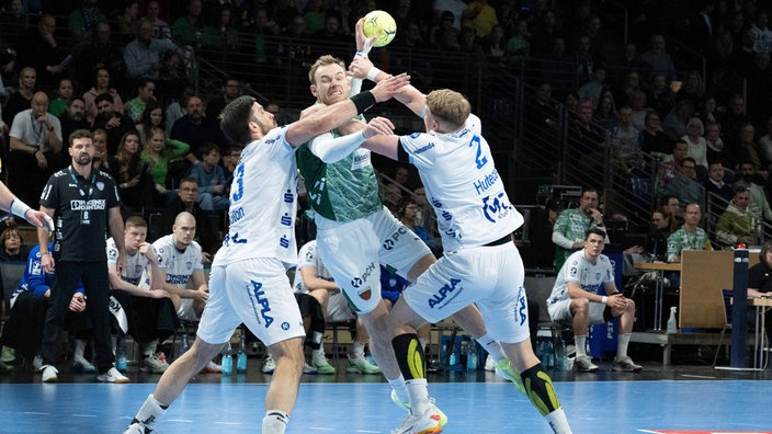 Tim Suton (links) und Lukas Hutecek (rechts) vom versuchen, Berlins Mathias Gidsel zu stoppen.