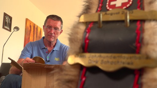Dirk Schachtsiek schaut sich eine Medaillen an.