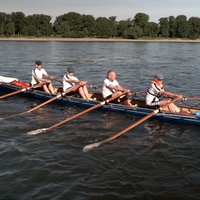 Auf einem Ruderboot sitzen fünf Ruderer, sie rudern konzentriert