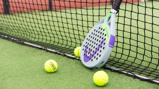Padelschläger und Bälle am Netz