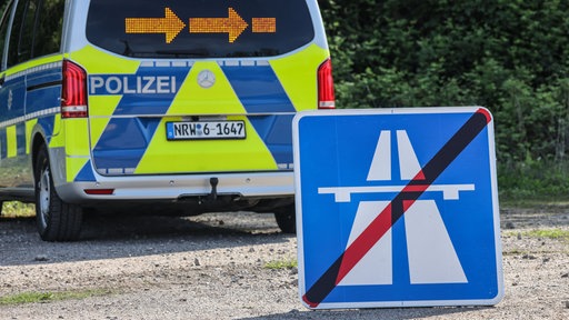 Ein Hinweisschild für eine gesperrte Autobahn steht beim Eigensicherungstag der Polizei Nordrhein-Westfalen vor einem Einsatzfahrzeug.