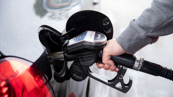 Ein Autofahrer steckt an einer Tankstelle einen Diesel-Zapfhahn in die Tanköffnung seines Fahrzeugs.