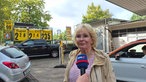 Eine Frau wird bei einer Tankstelle interviewt