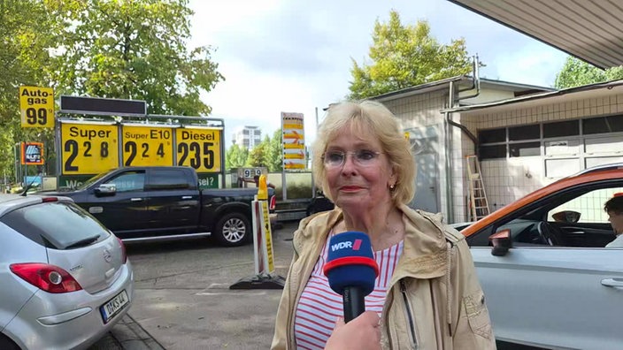 Eine Frau wird bei einer Tankstelle interviewt