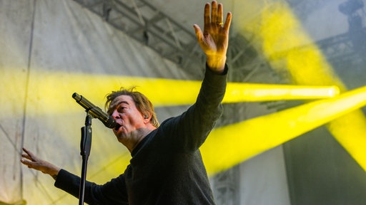 Sänger der Toten Hosen, Campino, steht auf einer Bühne und singt