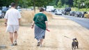 Zwei Personen gehen mit einem Hund über eine ausgetrocknete Wiese. Hürth, 17.07.2026.