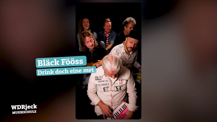 Die Band sitzt in einem engen Studio und spielt auf Kinderinstrumenten