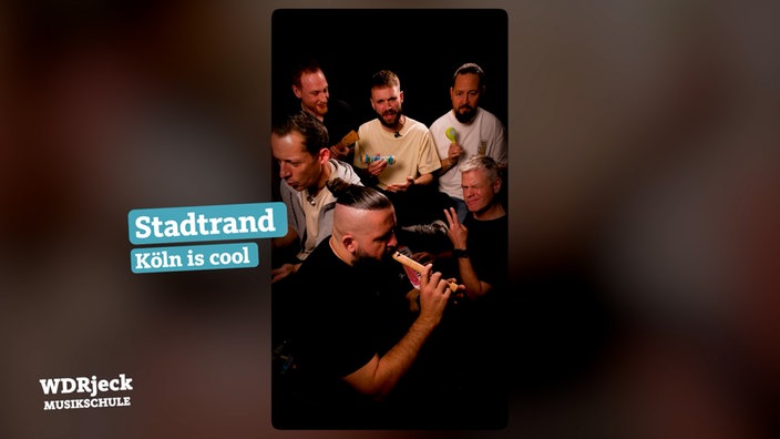 Die Band sitzt in einem engen Studio und spielt auf Kinderinstrumenten