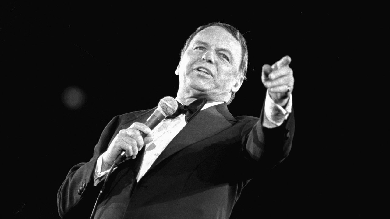 Frank Sinatra steht 1974 im Nassau Veterans Memorial Coliseum in Uniondale (Long Island, New York) am Mikrofon und zeigt in Richtung Kamera