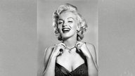 Porträtfoto von Filmikone Marilyn Monroe, die eine Kette um den Hals trägt und in die Kamera lacht (ca. 1952)