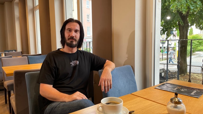 Ein Mann sitzt entspannt an einem Tisch im Café