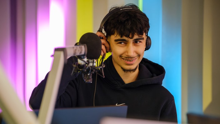 Ein junger Mann  steht vor einem Mikrofon