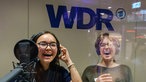 Zwei junge Frauen stehen in eine Aufnahmekabine und lachen
