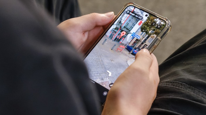 Ein Jugendlicher sucht in seinem Handy einen Ort