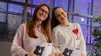 Zwei junge Frauen stehen nebeneinander und lächeln