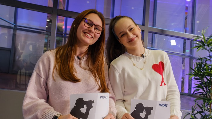 Zwei junge Frauen stehen nebeneinander und lächeln