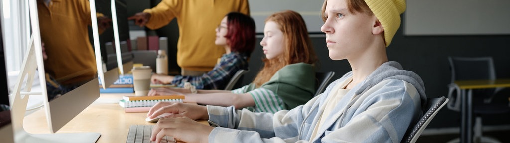 Schüler an PC, gelbe Mütze
