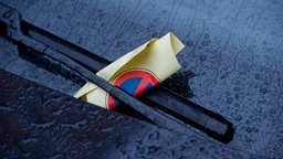 Windschutzscheibe mit Strafzettel hinter dem Scheibenwischer