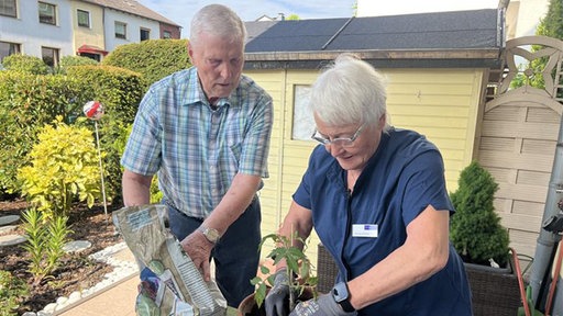 Rentnerin Monika Gomulia hilft anderen Rentnern im Alltag. Hier kümmert sie sich zusammen mit einem älteren Mann um Blumen.