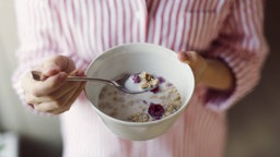 Das Bild zeigt eine Schale mit Milch und Früchtemüsli.