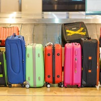 Das Bild zeigt viele Koffer nebeneinander am Kofferband am Flughafen.