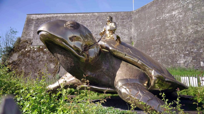Skulptur einer großen Schildkröte, auf der ein Reiter sitzt