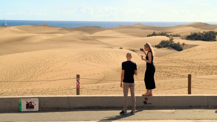 Zwei Touristen schauen auf die Dünenlandschaft von Maspalomas
