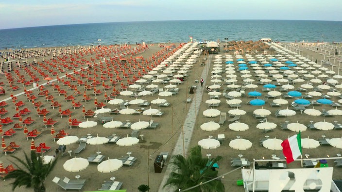 Endlose Reihen von verschiedenfarbigen Sonnenschirmen an einem Sandstrand
