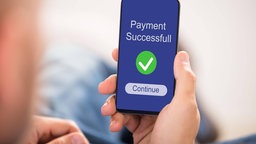 Eine Person überweißt Geld am Smartphone.