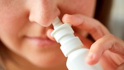 Eine Frau nutzt Nasenspray.