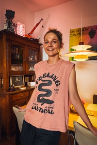 Andrea Prudlo lehnt an einem Esstisch und lächelt in die Kamera.