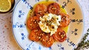 Geröstete Aprikosen mit cremiger Burrata und knusprigen Pinienkernen, serviert auf einem Teller.