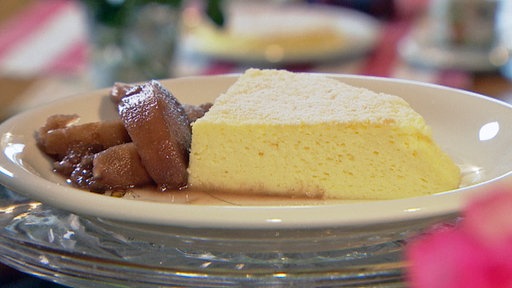 Ein heller Kuchen auf einem weißen Teller garniert mit Pflaumenmus.